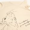 Front image of 'Kindess' tee. Hand patting cow sketch and phrase 'In a world where you can be anything, be kind'