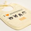 Front of ecru coloured baby bib. Orange Animals Australia logo. Cartoon images of a pig, kangaroo, chicken and fish face. Text - I "heart" everyone!