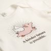 White baby tee with pic of a flying pig on it and the phrase 'A kinder future is possible.'