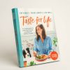 Front cover of 'Taste for Life' cookbook. Image of a person eating with a dog sitting by their side